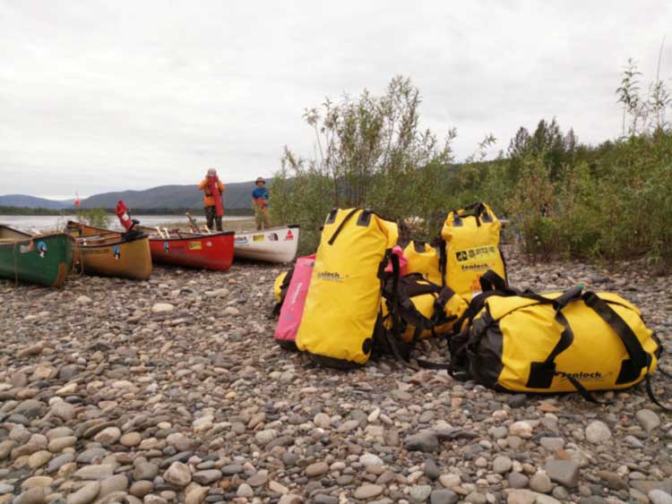 Camping gear laid out beside waterproof dry bags in stepped capacities showing what fits