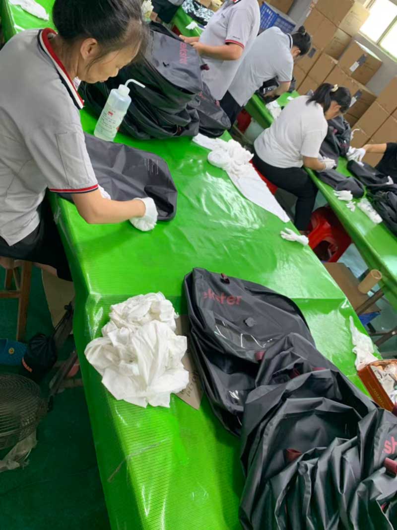 Operators in white gloves cleaning compression bag window panels with welding machines behind