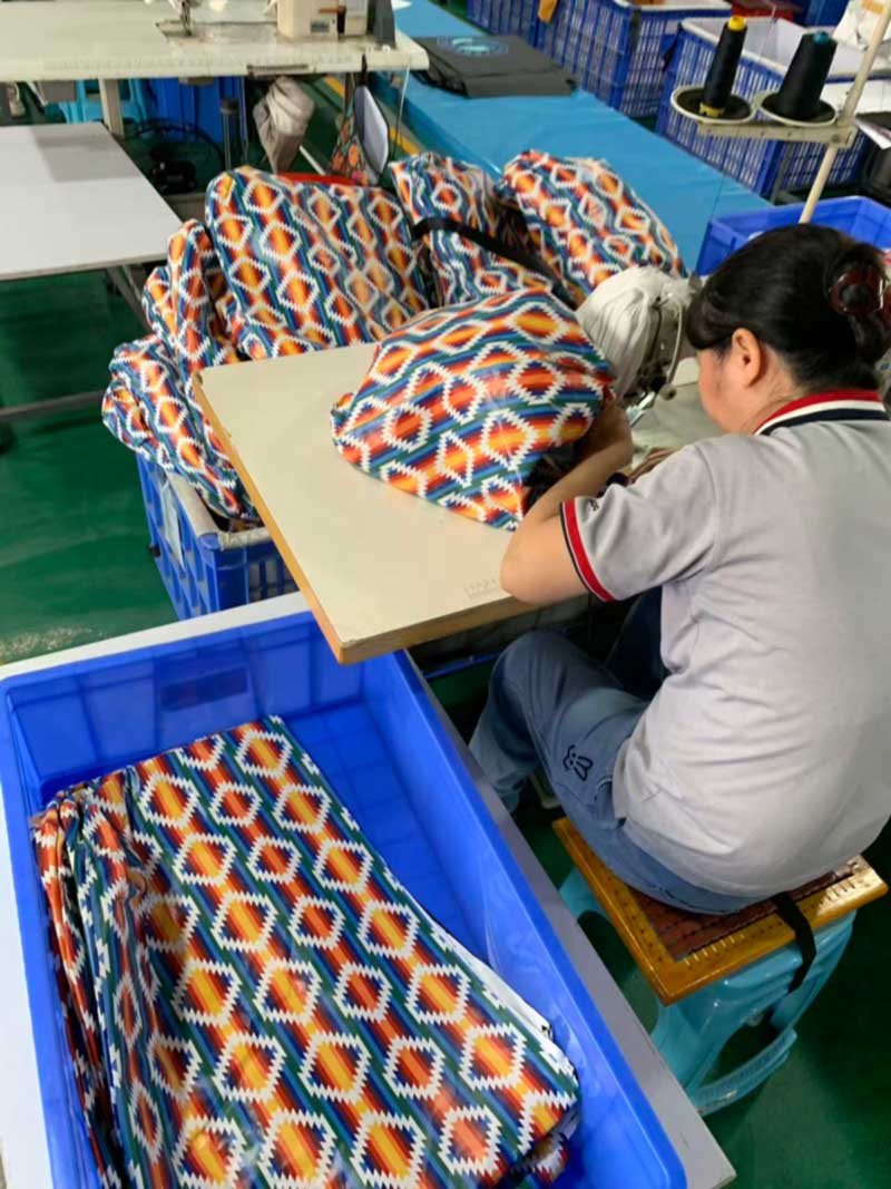 Printed coated fabric panels laid out at a welding station with cut pieces stacked alongside
