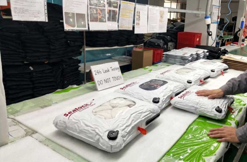 Compressed vacuum bags filled with clothes resting on an inspection table during a 24-hour air-leak check